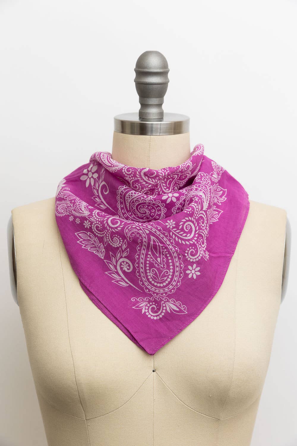 Magenta purple paisley print bandana tied around a dress form mannequin, featuring a white floral and teardrop paisley pattern
