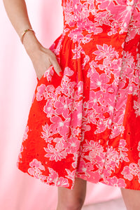 Close-up of red and pink floral eyelet skirt with side pocket detail on a fit-and-flare mini dress