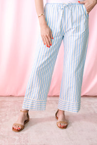 Blue and white vertical striped wide-leg crop pants with contrast hem detail, styled with tan ankle strap sandals