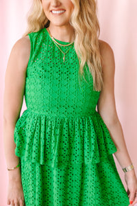 Close-up of fitted bodice and crew neckline on a bright green eyelet sleeveless midi dress with double tiered ruffle skirt detail
