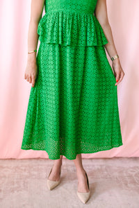 Close-up of bright green eyelet double tiered ruffle midi skirt with A-line silhouette and scalloped hem, paired with nude pointed-toe heels