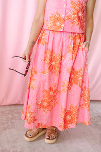 Close-up of pink and orange floral eyelet A-line maxi skirt with elasticized waist and side pocket, paired with platform sandals