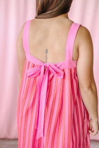 Back view of pink multicolor vertical stripe maxi dress showing wide square-cut straps and pink bow tie detail at the waist