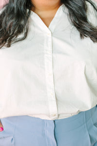 Close-up of button placket and relaxed fit on white cotton poplin button-down top 
