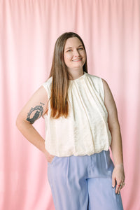 Sleeveless pleated balloon top in cream worn with periwinkle wide-leg pants — front view
