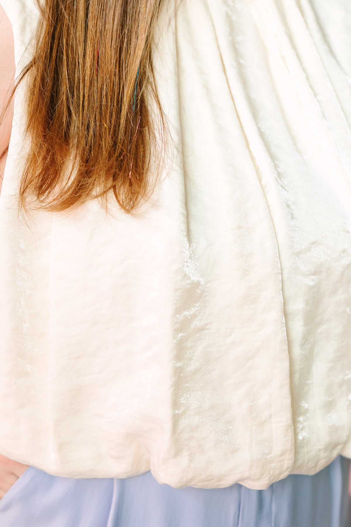 Back and side view of cream sleeveless balloon top showing scalloped hem and pleated texture detail