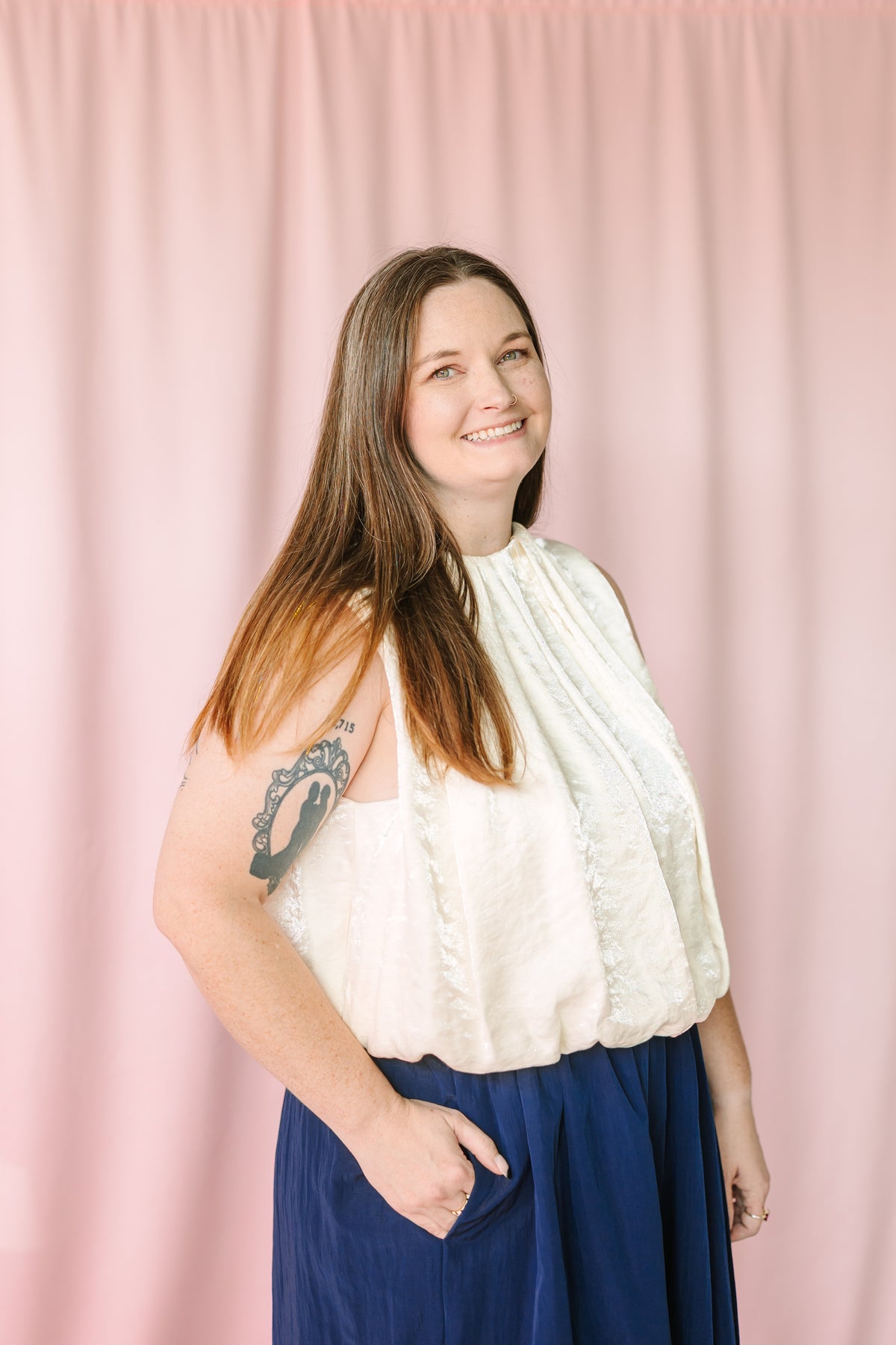 Sleeveless pleated balloon top in cream styled with navy wide-leg skirt — side view