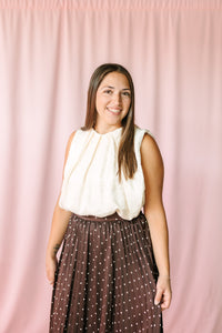 Cream sleeveless pleated balloon top styled with brown polka dot midi skirt — front view