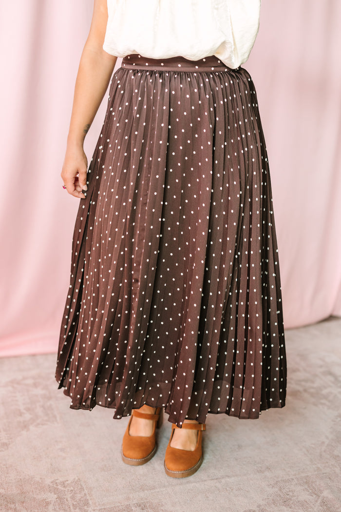 Chocolate brown polka dot pleated maxi skirt with white dot print and elastic waistband, styled with tan Mary Jane platform shoes