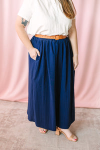 Navy blue gathered maxi skirt with elastic waist, tan leather belt, and side pocket detail