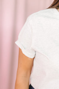 Close-up of rolled short sleeve on heather gray slub-knit tee against pink backdrop
