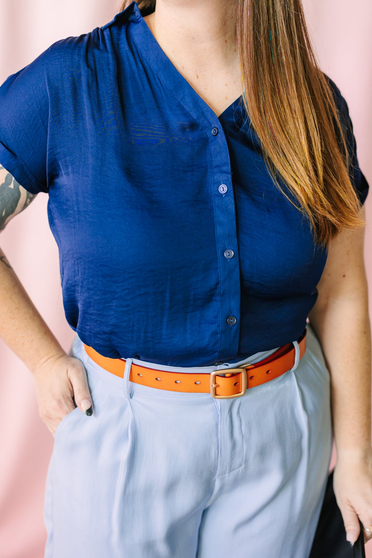 Navy blue short-sleeve button-front blouse with gathered neckline detail, paired with light blue wide-leg pants and brown leather belt