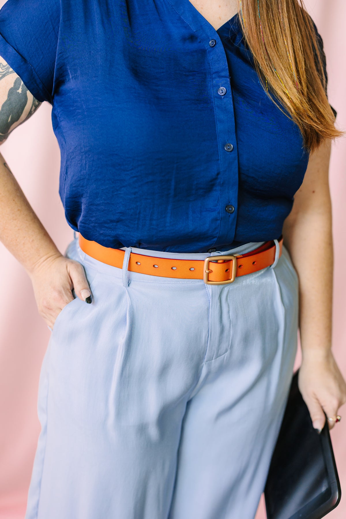 Navy blue short-sleeve button-down blouse with dark buttons, styled with light blue wide-leg trousers and a brown leather belt with gold buckle