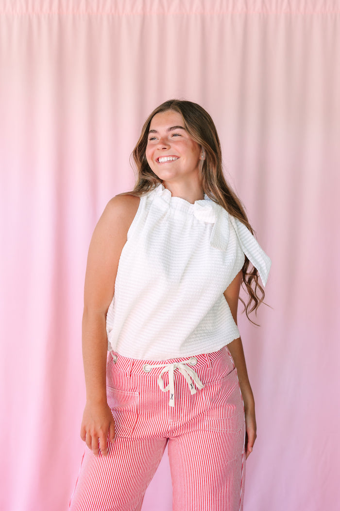 White Ruffle Neck Tie Blouse with ruffle neckline and neck tie, paired with red striped pants — three-quarter view