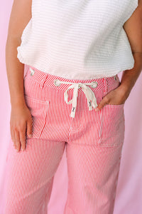 Close-up of Pinstripe Barrel Pants showing red and white stripe detail, adjustable drawstring waist, and front pockets