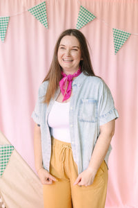 Woman in light wash denim short-sleeve button-down shirt with pink bandana and mustard wide-leg pants, front view
