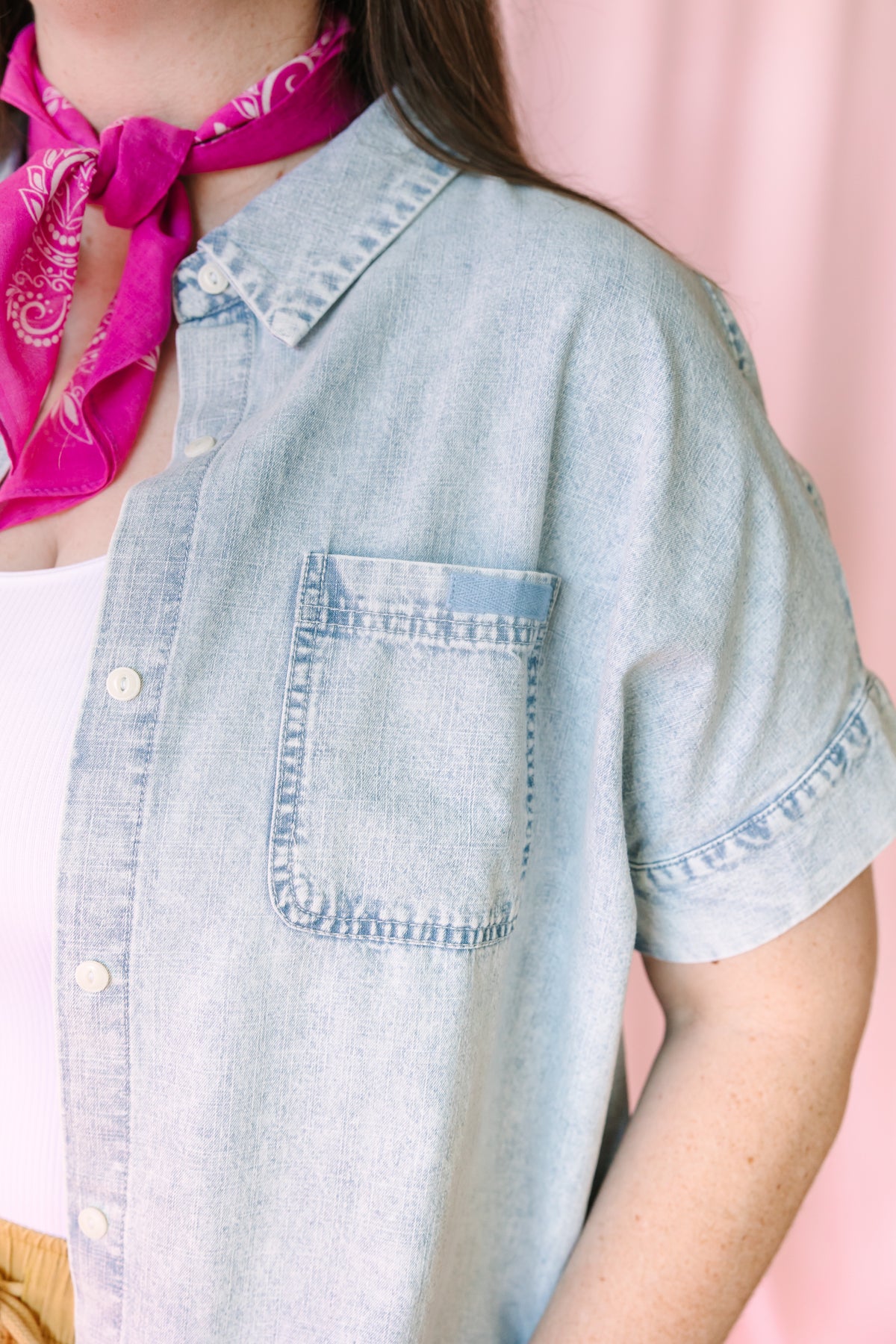 Close-up detail of light wash chambray shirt showing chest pocket and ruffle sleeve trim