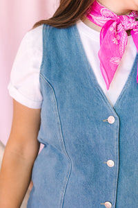 Close-up of V-neck button-front denim dress detail showing silver snap buttons and seam construction, styled with a white tee underneath and pink paisley bandana