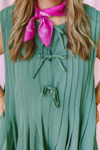 Close-up of sage green pleated romper V-neckline with self-tie bow detail and pink bandana scarf
