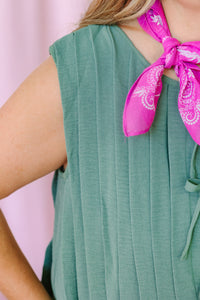 Close-up of sage green pleated romper fabric with tie front neckline and pink paisley bandana scarf detail
