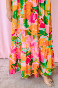 Detail shot of tiered ruffle hem on a bright tropical floral maxi dress in orange, pink, and green