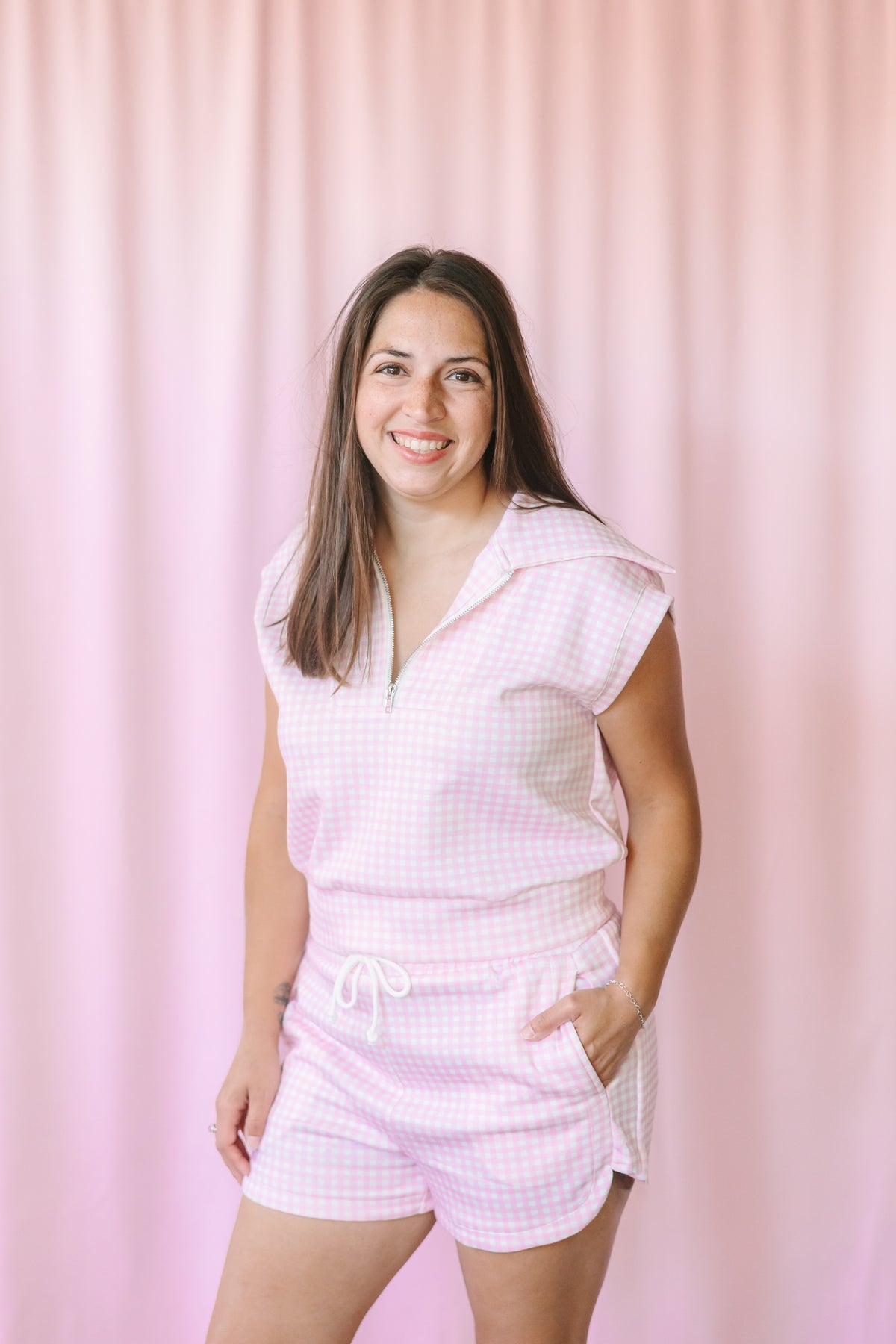 Woman wearing pink gingham matching set with half-zip top and drawstring shorts, styled with tan platform sandals