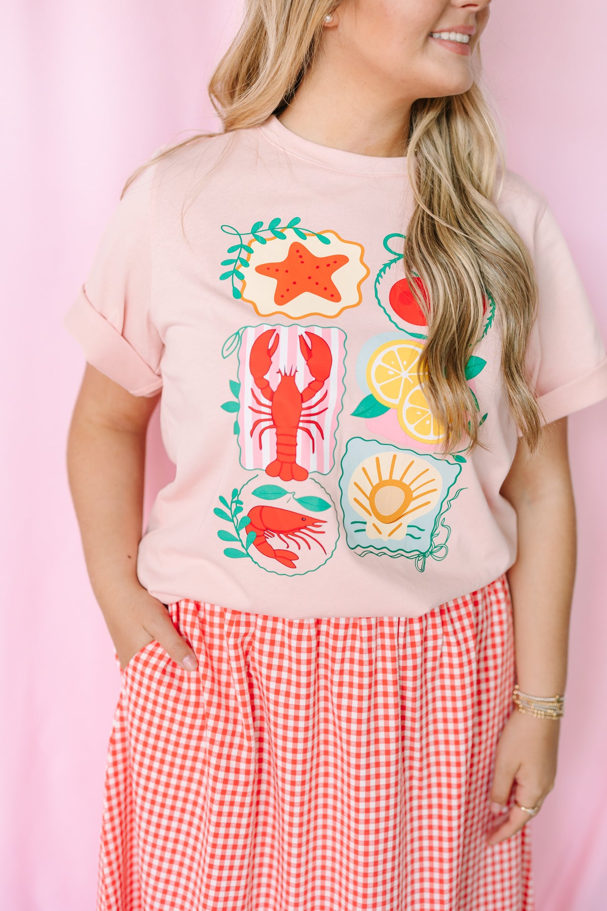 Women's pink nautical graphic tee, styled view with beach-inspired design
