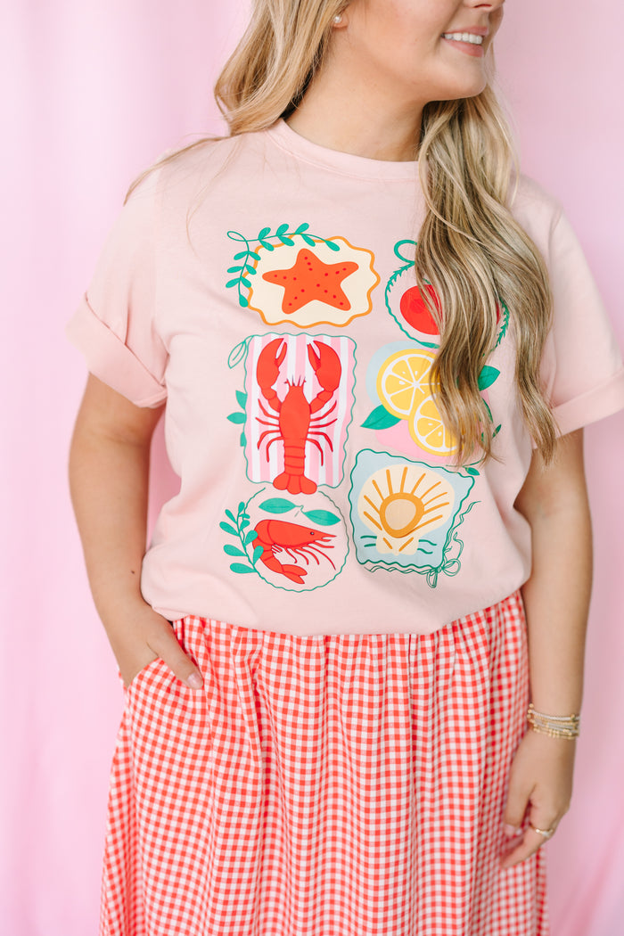 Women's pink nautical graphic tee, styled view with beach-inspired design